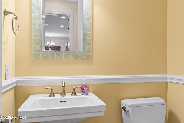 bathroom with an inviting chandelier, sink, and toilet