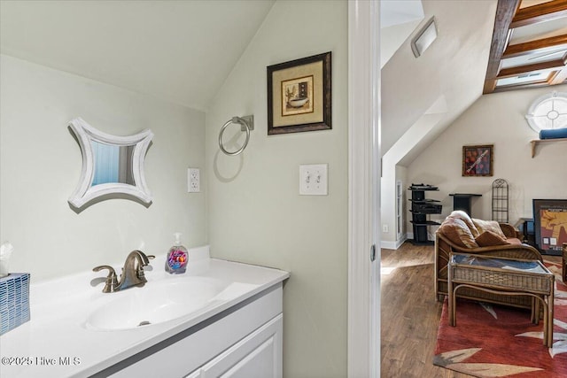 bathroom featuring hardwood / wood-style flooring, vanity, and vaulted ceiling with skylight