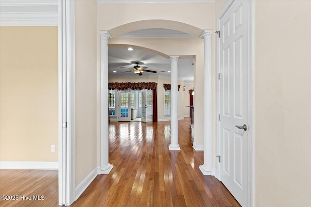 hallway with crown molding, wood-type flooring, and decorative columns