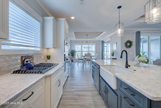 kitchen featuring white cabinets, decorative light fixtures, tasteful backsplash, and a tray ceiling