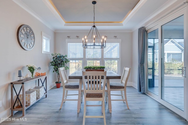 dining area featuring an inviting chandelier, a raised ceiling, and dark wood-type flooring