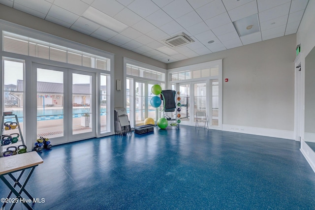 exercise room featuring a drop ceiling, a healthy amount of sunlight, and french doors