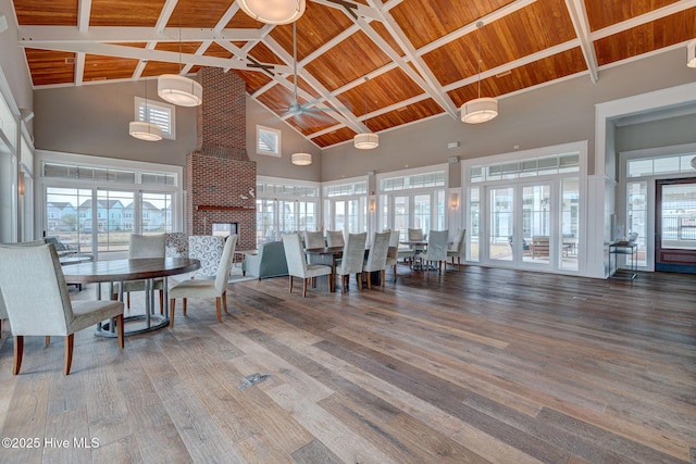 dining area with hardwood / wood-style floors, high vaulted ceiling, ceiling fan, a fireplace, and wood ceiling