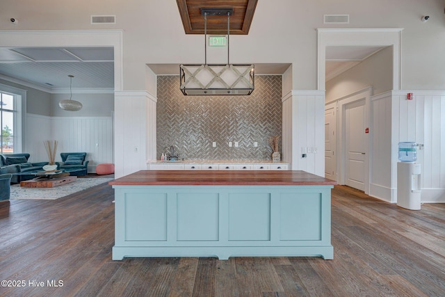 kitchen featuring dark hardwood / wood-style flooring, wooden counters, hanging light fixtures, and ornamental molding