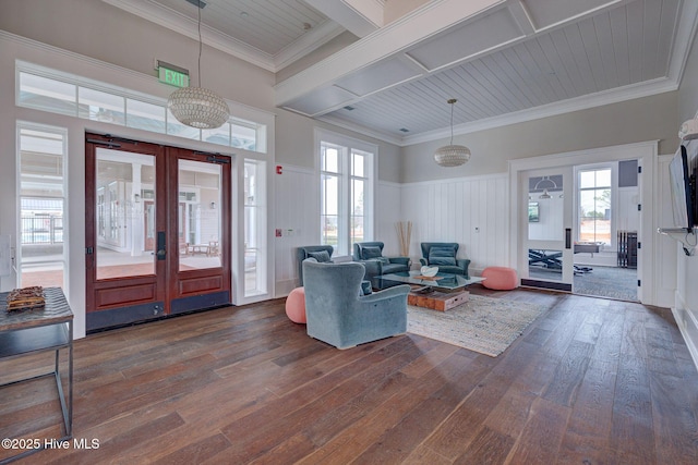 living room featuring dark hardwood / wood-style flooring, crown molding, french doors, and an inviting chandelier