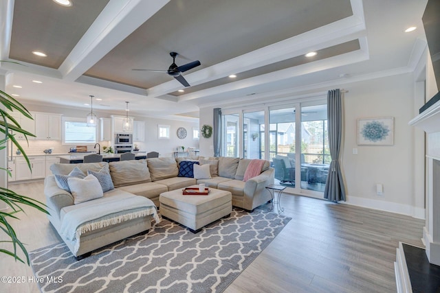 living room with light wood-type flooring, ceiling fan, crown molding, and sink