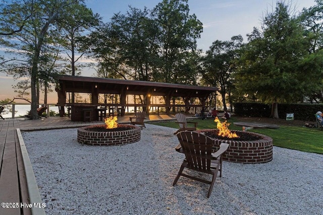 back house at dusk featuring an outdoor fire pit and a wooden deck