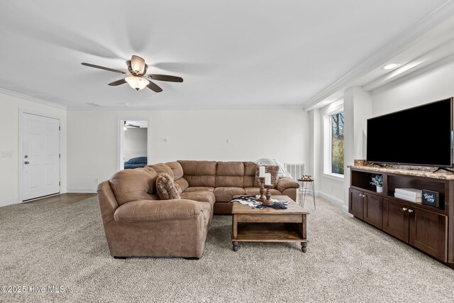 living room with ceiling fan, ornamental molding, and light carpet