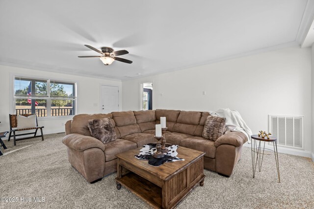 living room featuring ceiling fan, crown molding, and light colored carpet