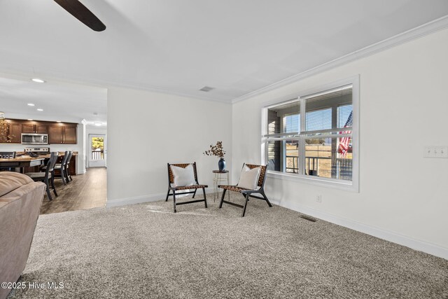 sitting room featuring ceiling fan, carpet floors, and ornamental molding