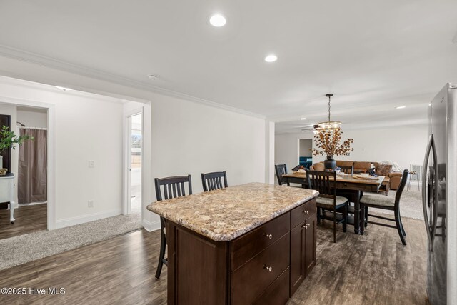 kitchen featuring a breakfast bar, a center island, decorative light fixtures, dark brown cabinets, and stainless steel refrigerator