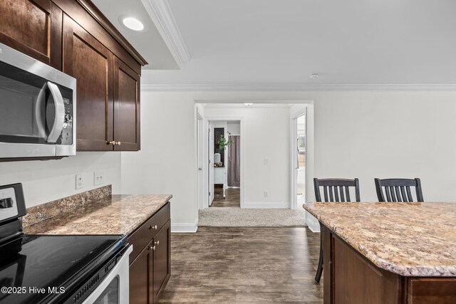 kitchen with stainless steel appliances, a kitchen breakfast bar, dark hardwood / wood-style flooring, dark brown cabinets, and ornamental molding