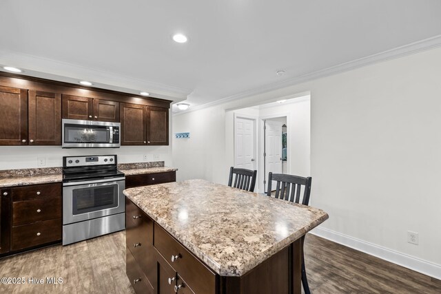 kitchen with a breakfast bar, appliances with stainless steel finishes, a center island, and crown molding