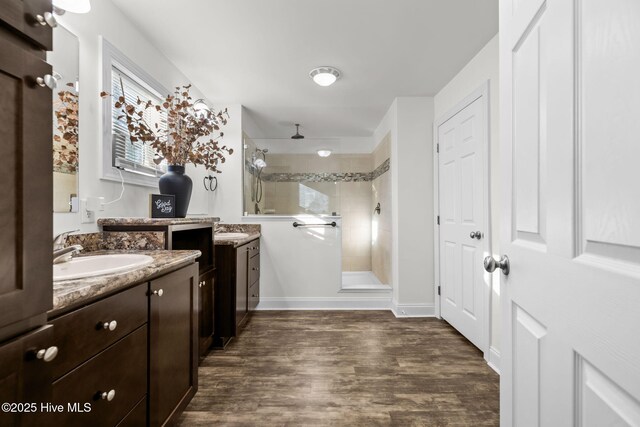 bathroom with tiled shower, wood-type flooring, and vanity