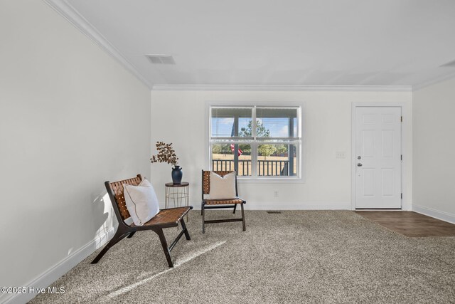 living area with crown molding and carpet