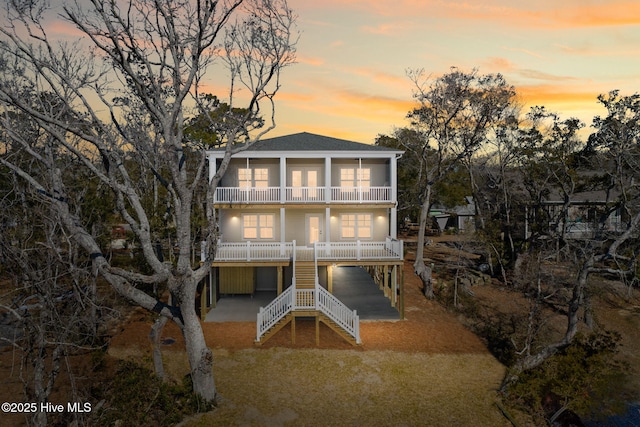 back of property featuring stairway, a balcony, and roof with shingles