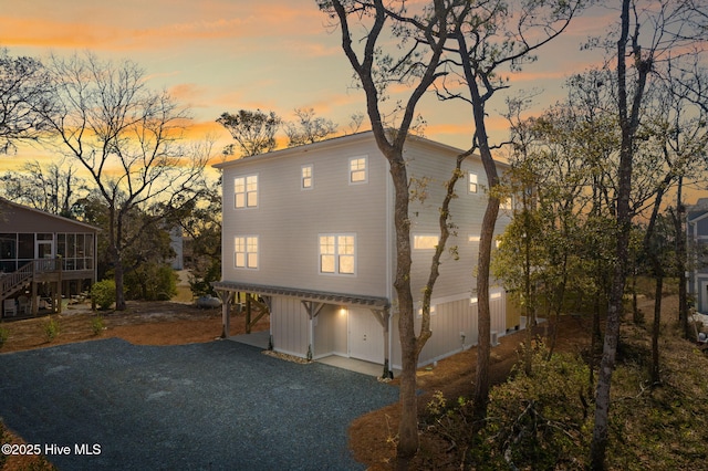 view of front of property with a carport, stairway, gravel driveway, and a sunroom