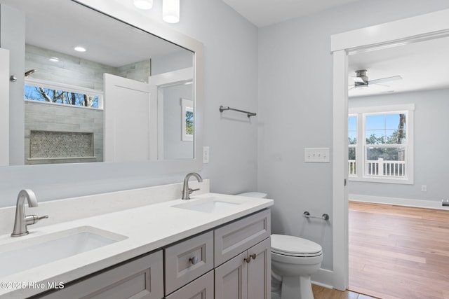 full bath with toilet, wood finished floors, a tile shower, and a sink