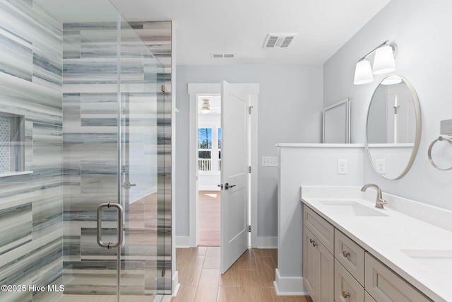 bathroom featuring double vanity, visible vents, a shower stall, and a sink