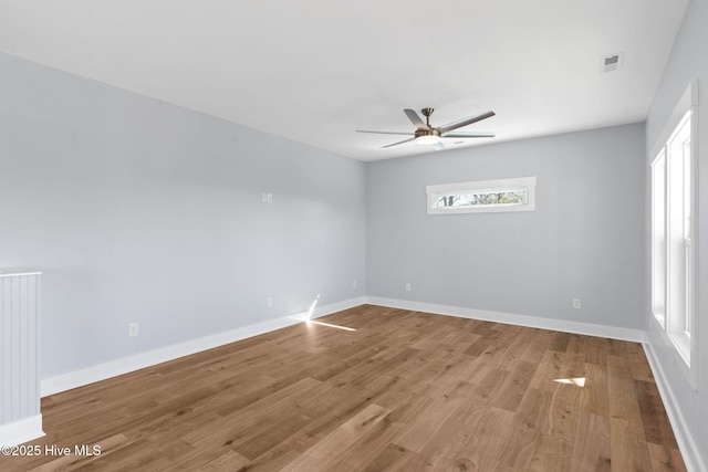 spare room featuring visible vents, baseboards, ceiling fan, and wood finished floors