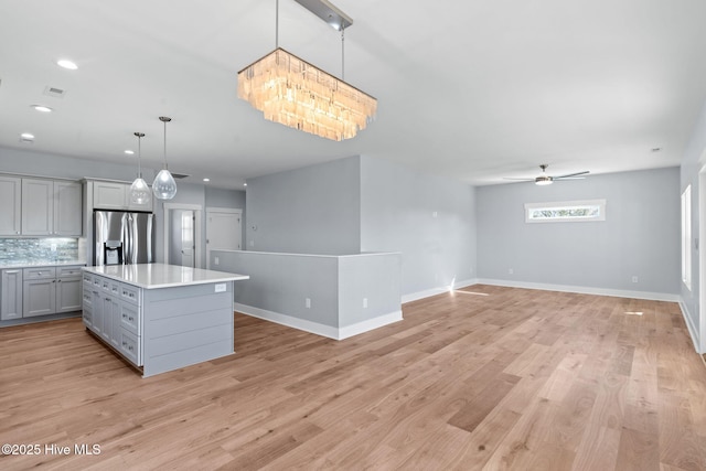 kitchen featuring open floor plan, light wood-style floors, stainless steel fridge, and gray cabinetry