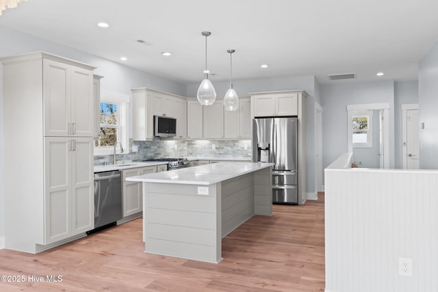 118 SE 9th St, Oak Island, NC 28465 - kitchen with appliances with stainless steel finishes, decorative backsplash, light countertops, a center island, and light wood-style floors