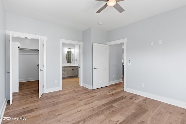 unfurnished bedroom with a walk in closet, baseboards, ensuite bathroom, light wood-style floors, and a closet