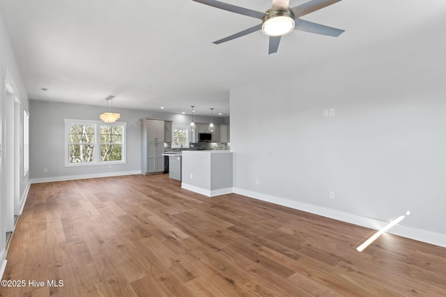 unfurnished living room featuring a ceiling fan, baseboards, and light wood finished floors