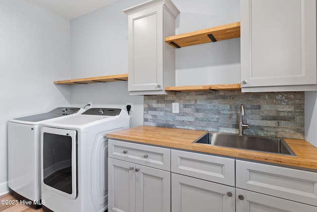 washroom featuring indoor wet bar, washing machine and clothes dryer, cabinet space, and a sink