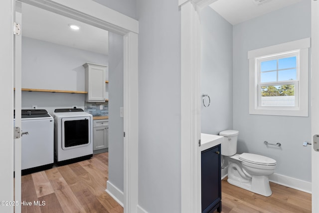 laundry area with washer and dryer, baseboards, light wood-style flooring, and laundry area