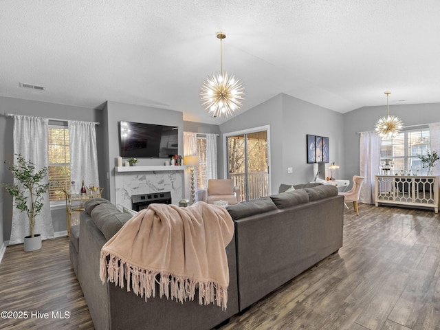 living room featuring a premium fireplace, hardwood / wood-style floors, a chandelier, and vaulted ceiling