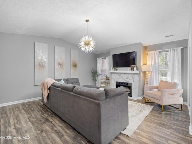 living room with a high end fireplace, a textured ceiling, and an inviting chandelier