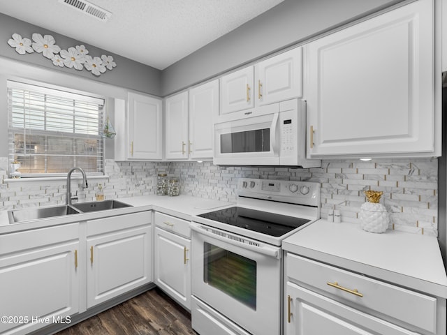 kitchen featuring a textured ceiling, white cabinetry, sink, and white appliances