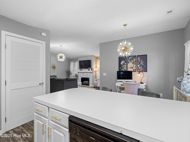 kitchen with dark wood-type flooring, black dishwasher, a notable chandelier, decorative light fixtures, and white cabinets