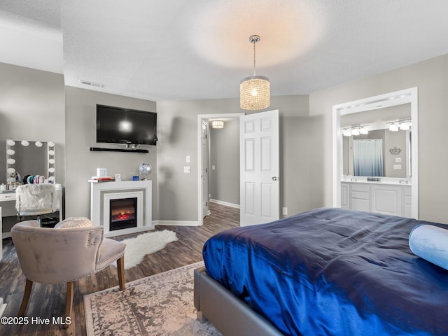 bedroom featuring hardwood / wood-style flooring, ensuite bathroom, and a textured ceiling