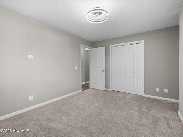 unfurnished bedroom with carpet floors, a textured ceiling, and a closet