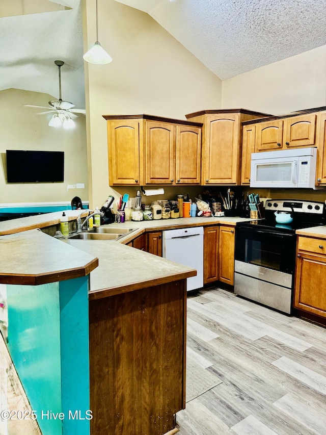 kitchen featuring sink, kitchen peninsula, pendant lighting, white appliances, and light hardwood / wood-style floors