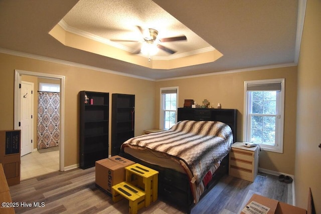 bedroom with crown molding, a tray ceiling, ceiling fan, and hardwood / wood-style flooring