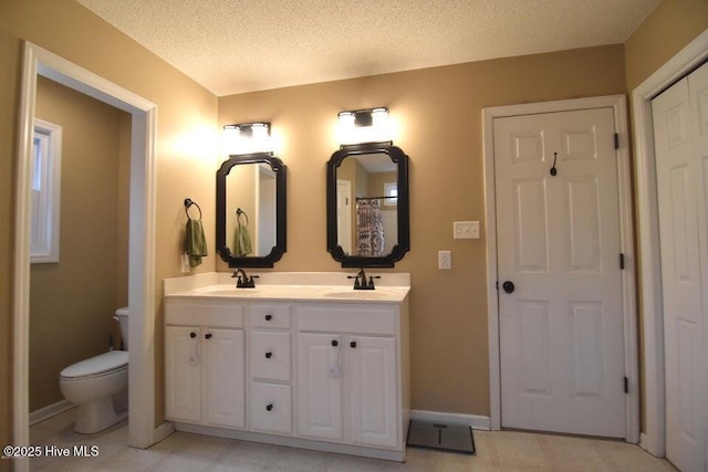 bathroom featuring vanity, a textured ceiling, and toilet