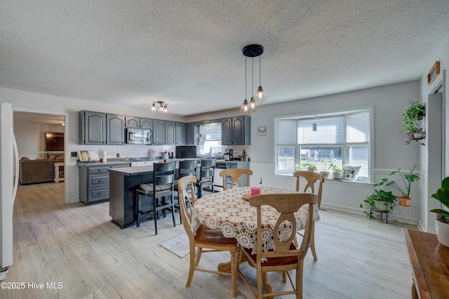 dining area with light hardwood / wood-style flooring and a textured ceiling