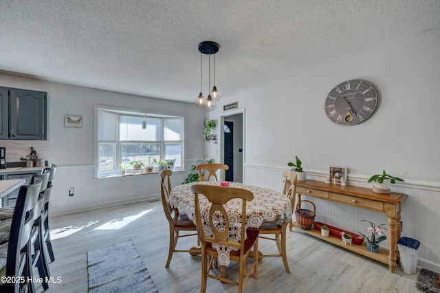 dining space with light hardwood / wood-style floors and a textured ceiling