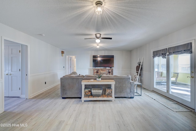 living room featuring ceiling fan, a textured ceiling, and light hardwood / wood-style flooring