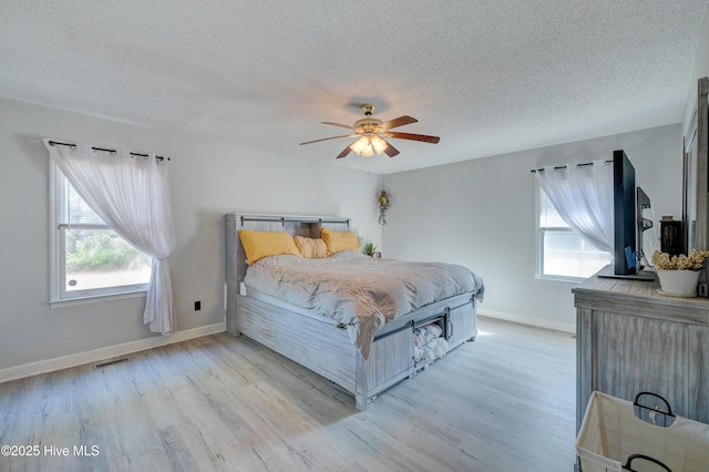 bedroom with ceiling fan, a textured ceiling, and light hardwood / wood-style flooring