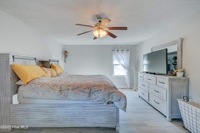 bedroom with ceiling fan, light hardwood / wood-style floors, and a textured ceiling