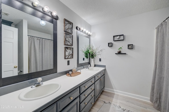 bathroom with hardwood / wood-style flooring, vanity, and a textured ceiling