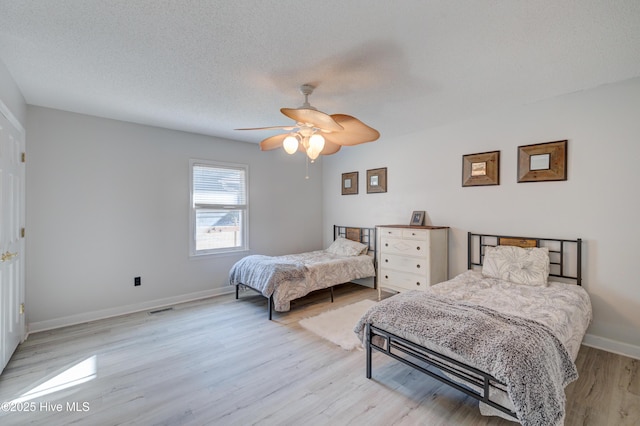 bedroom featuring ceiling fan, light hardwood / wood-style floors, and a textured ceiling