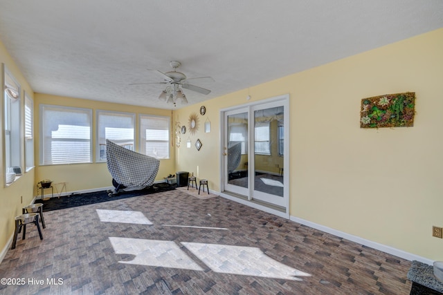 unfurnished sunroom featuring ceiling fan