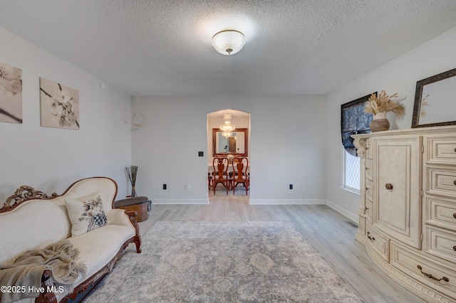 sitting room with light wood-type flooring and a textured ceiling