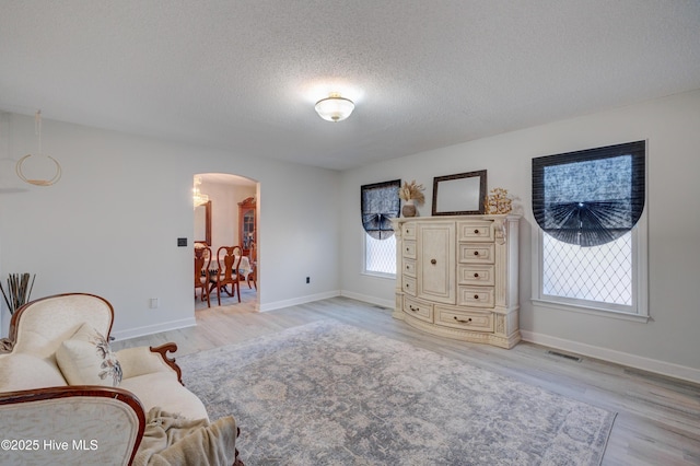 living area with light wood-type flooring and a textured ceiling