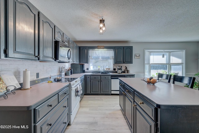 kitchen featuring dishwasher, sink, a center island, and electric range oven